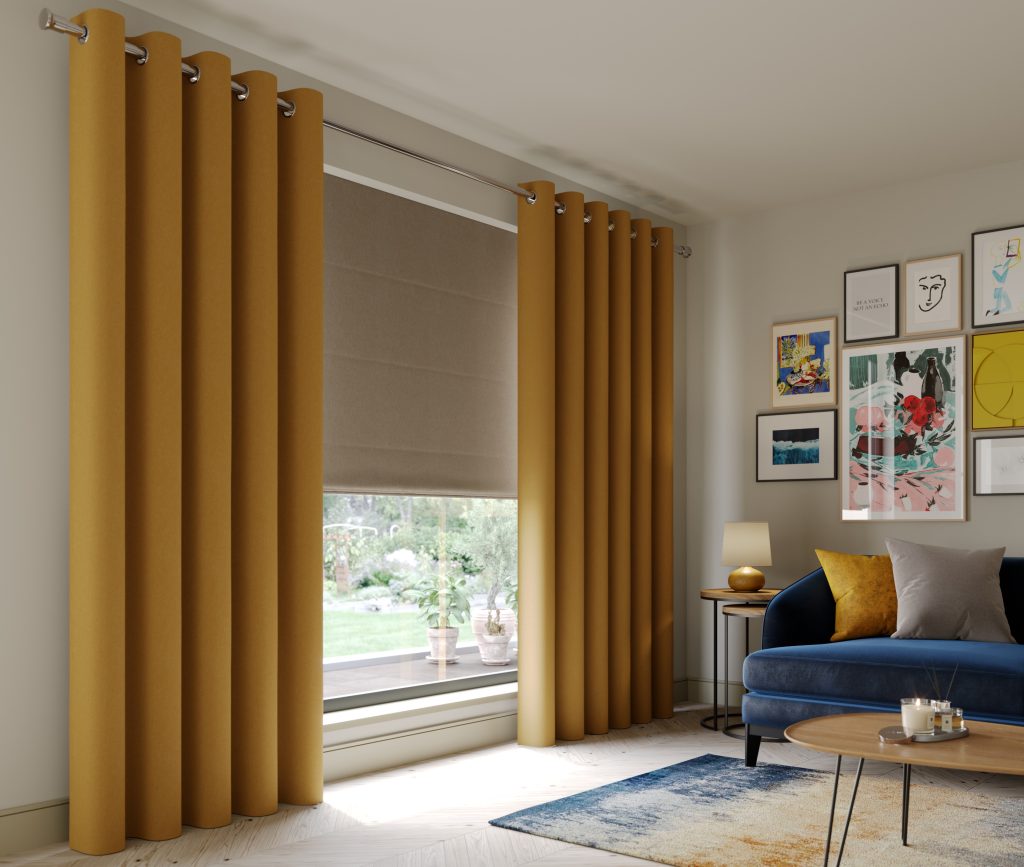 Mustard yellow curtains frame a large window with taupe roman blind in a living room with navy blue sofa and gallery wall art