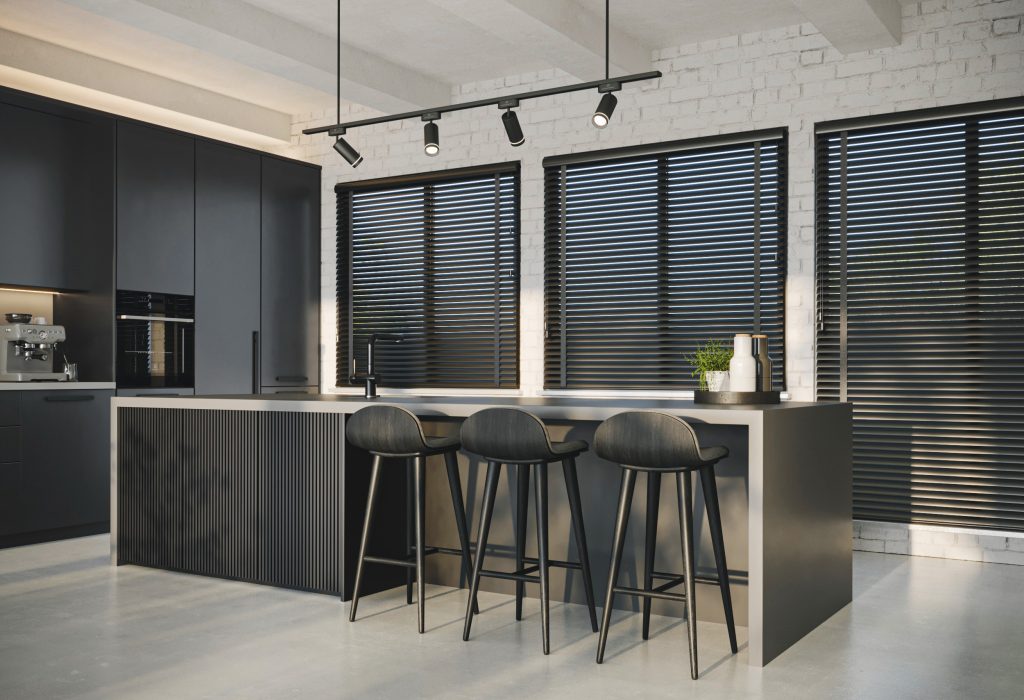 Modern kitchen with dark cabinets, fluted island, three black bar stools, track lighting, and black-slat blinds on windows.